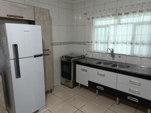 uma cozinha com um frigorífico branco e um lavatório em 10 MIN AEROPORTO GUARULHOS em Guarulhos