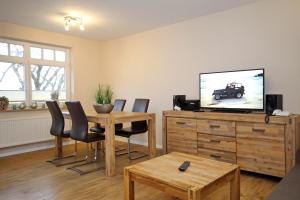 uma sala de estar com uma televisão e uma mesa e cadeiras em Villa Hanse Wohnung 312 em Kühlungsborn