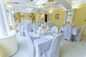 a dining room with white tables and white chairs at Tavria Hotel in Simferopol
