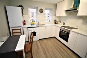 a kitchen with white cabinets and a table and a dishwasher at Superb 2 Bed Apartment in Finnieston, Close to SEC, Hydro and City Centre in Glasgow