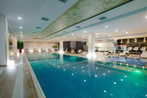a large pool in a hotel with chairs and tables at Somerset City Centre Atyrau in Atyraū