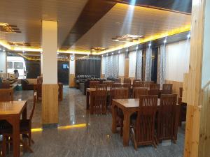 a dining room with wooden tables and chairs at Tulip Flowing River View Hotel. in Shamshi