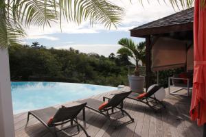 a deck with chairs and a table next to a swimming pool at Villa Kouleur Kafé in Sainte-Anne
