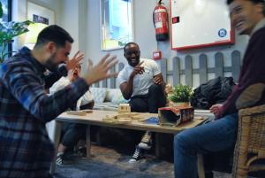 un groupe de personnes assises autour d'une table jouant à un jeu dans l'établissement Quartier Bilbao Hostel, à Bilbao