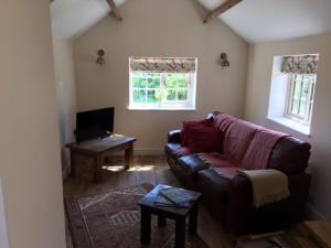 a living room with a couch and a table at Cosy getaway near Rutland Water in Oakham