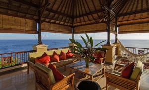 a porch with a couch and chairs and the ocean at Villa Batu Tangga in Amed