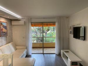sala de estar con sofá y puerta corredera de cristal en Résidence Les Eucalyptus, en Antibes