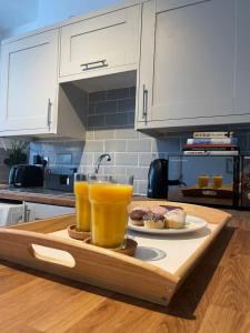 a tray with two glasses of orange juice and cupcakes on a kitchen counter at Judah Suites by Koya Homes in Barry