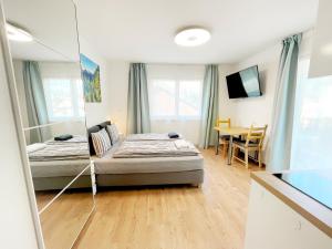 1 dormitorio con 2 camas, mesa y espejo en Apartments ALPsmart, en Oetz