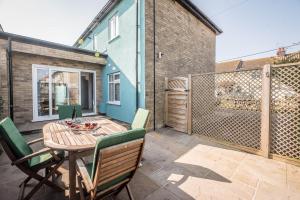 een patio met een houten tafel en stoelen bij Swifts in Southwold