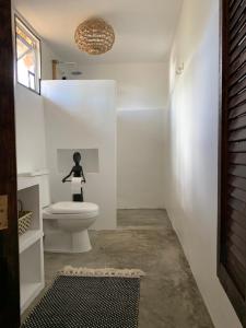 a bathroom with a toilet and a statue of a woman at Three Little Birds Resort in Anda