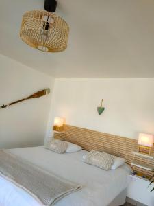 a bed with two pillows and two lights on the wall at Émeraude in Penmarch