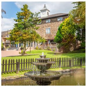 a fountain in front of a building with a clock tower at Last Drop Village Hotel & Spa in Bolton