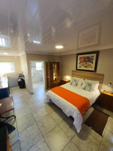 a bedroom with a large bed with an orange blanket at Huis van Seisoene in Klerksdorp