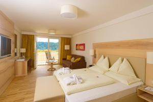 a bedroom with a large bed and a living room at Hotel & Spa Sonne in Sankt Kanzian