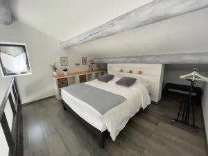 1 dormitorio con 1 cama blanca grande y escritorio en Gîtes dans Mas en pierres, en Robion en Luberon