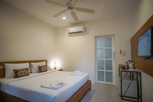 a bedroom with a large bed with a ceiling fan at Capricorn Village - SHA Extra Plus in Patong Beach