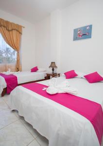 two beds with pink and white sheets in a room at Paraiso de Isabela in Puerto Villamil