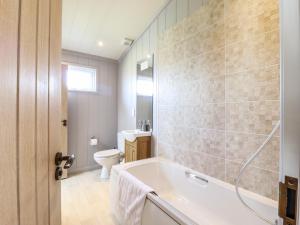 a bathroom with a tub and a toilet at Skylarks in Hengrave +24 photos