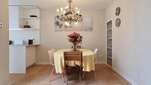 a dining room with a table with a vase of flowers on it at Opening Doors Vilassar. Family house Beach & Relax in Vilassar de Mar