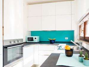 d'une cuisine avec des placards blancs et des touches de bleu. dans l'établissement The Best Rent - Apartment near Arco della Pace, à Milan