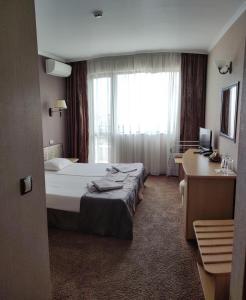 a hotel room with a bed and a desk and a window at Guest House Palazzo in Byala