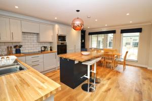 a kitchen with white cabinets and a wooden counter top at BY THE BEACH cottage, dogs welcome in Saint Merryn
