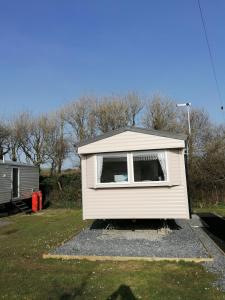 a tiny house with a window in a yard at Sycamores Caravan in Helston
