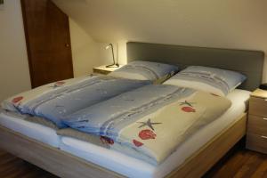 ein Bett mit zwei Kissen und einer blauen Bettdecke in der Unterkunft MEI27a Ferienwohnung Ostseetraum in Niendorf