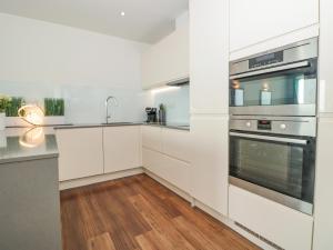 une cuisine avec des armoires blanches et des appareils en acier inoxydable dans l'établissement 18 Abbey Sands, à Torquay