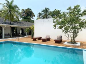une piscine avec deux bancs et une maison dans l'établissement Bella Vita, à Aluthgama