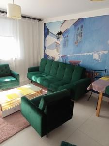 een woonkamer met een groene bank en stoelen bij Apartament Anita in Mielec