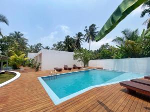 a swimming pool on a wooden deck next to a villa at Bella Vita in Aluthgama