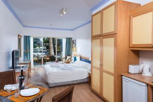 a room with a bed and a kitchen with a table at Paphos Gardens Holiday Resort in Paphos