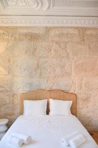 1 cama con sábanas y almohadas blancas frente a una pared de ladrillo en Lindo, funcional e charmoso espaço - Porto - APT H en Oporto
