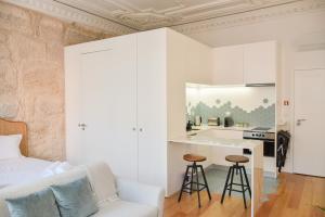 a white kitchen with a white couch and stool at Lindo, funcional e charmoso espaço - Porto - APT H in Porto