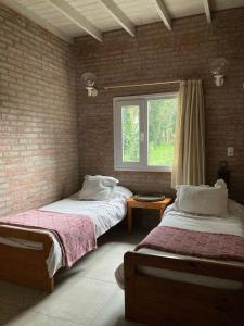 two beds in a room with a window at Duplex Las Margaritas Bosque Peralta Ramos in Mar del Plata