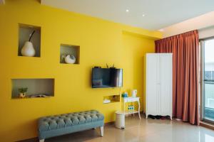 a yellow living room with a couch and a tv at Elsa House in Tainan