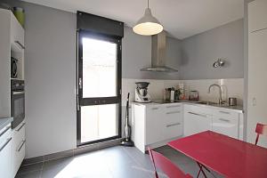 トゥールーズにあるT3 Saint Sernin apartmentの白いキャビネットと赤いテーブル付きのキッチン