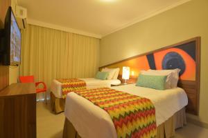 um quarto de hotel com duas camas e uma televisão em Malai Manso Resort Yatch Convention & Spa em Retiro