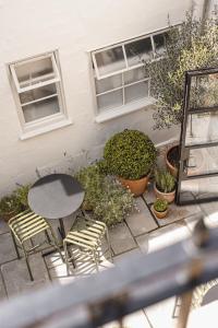 a patio with a table and chairs and plants at The Yard in Bath Hotel in Bath