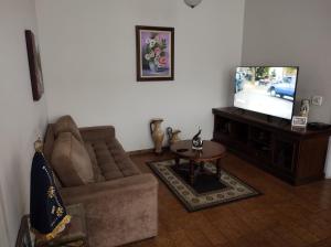 a living room with a couch and a television at Casa ótima e localização excelente em Aparecida-SP in Aparecida