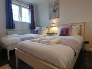 a bedroom with two beds with white sheets and purple pillows at Acer Holiday Cottage Tideswell village Buxton Peak District by Rework Accommodation in Tideswell