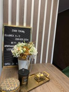 a table with a vase with flowers and a gold tray at Apartman Stari Toranj in Vukovar