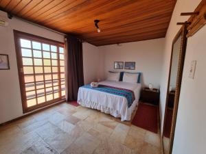 een slaapkamer met een bed en een groot raam bij Pousada Ikabana in Pirenópolis