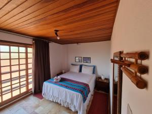 1 dormitorio con 1 cama con techo de madera en Pousada Ikabana, en Pirenópolis