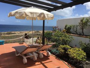 einen Stuhl und einen Regenschirm auf einer Terrasse mit Meerblick in der Unterkunft Paz del Mar in Charco del Palo + 9 Fotos
