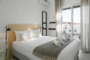 a bedroom with a large white bed with towels on it at Sunny Penthouse in Ferrel