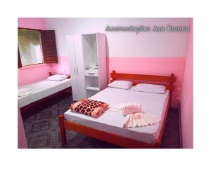 a bedroom with two beds and a pink wall at Pousada Asa Branca in Soure