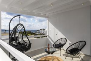 einen Balkon mit 2 Stühlen und einem Glastisch in der Unterkunft Sunset Windmills Suites in Mykonos Stadt